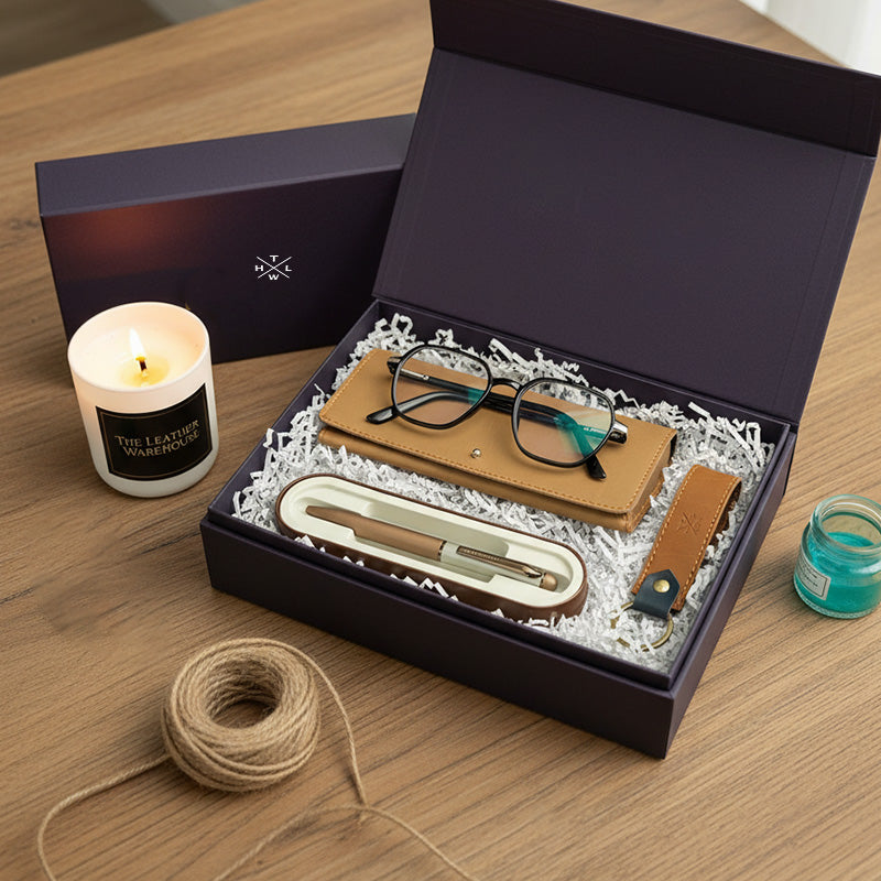 Gift set with eyeglasses, leather strap, and other items in a box on a wooden surface.