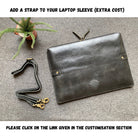 Black leather laptop sleeve with an additional strap on a gray surface.