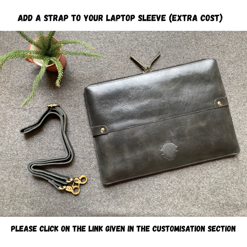 Black leather laptop sleeve with an additional strap on a gray surface.