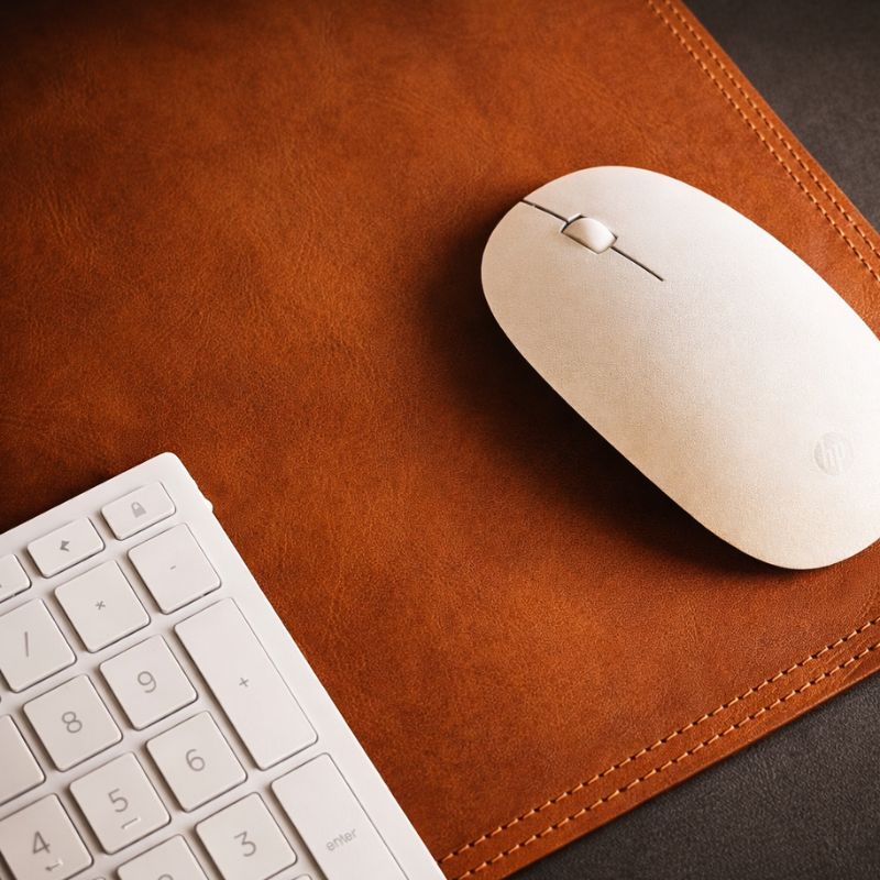 White keyboard and mouse on a brown leather deskmat
