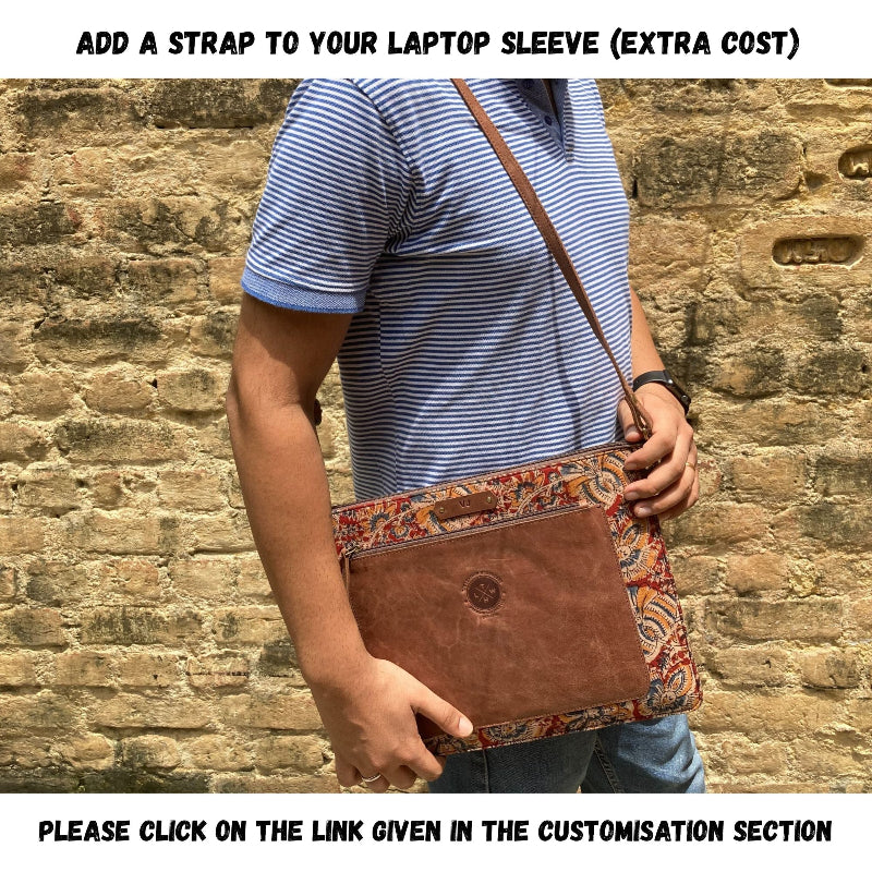 Person holding a brown leather bag with a patterned strap against a brick wall.