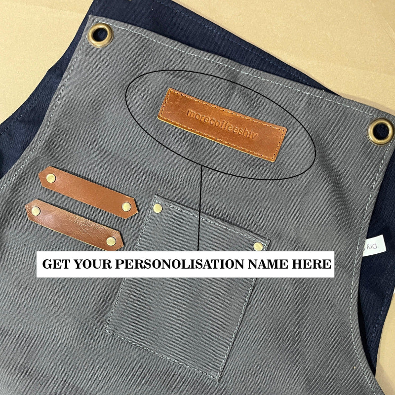 Gray apron with brown leather patches and a brand label on a beige background