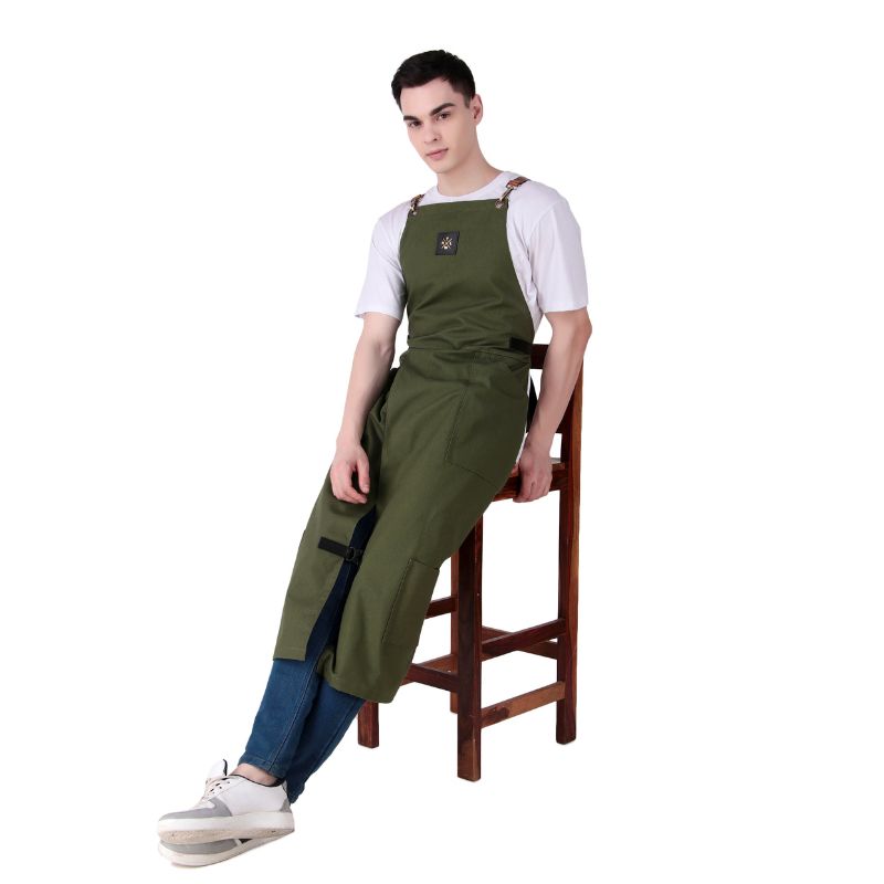 Person wearing a green apron sitting on a wooden stool against a white background