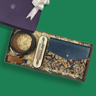 Gift set with blue leather wallet, belt, and pen in a box on a green background