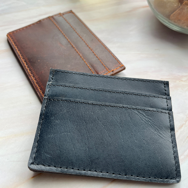 Black leather cardholder on a light wooden surface