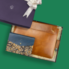 Brown leather sleeve with decorative interior and blue kalamkari diary on a green background