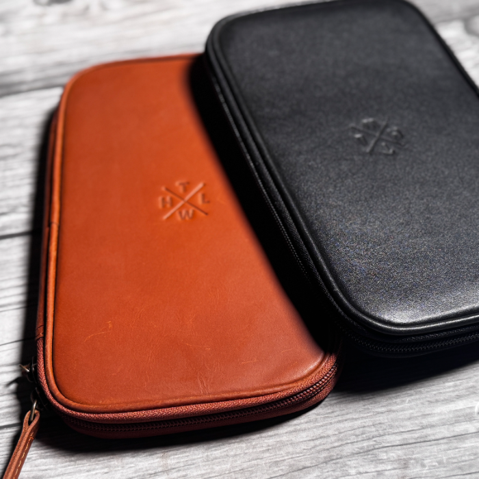 Brown and black leather cases with a visible brand logo on a wooden surface