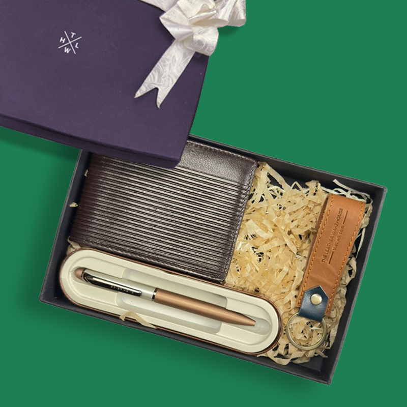 Gift set with pen, notebook, and leather item in a box on a green background