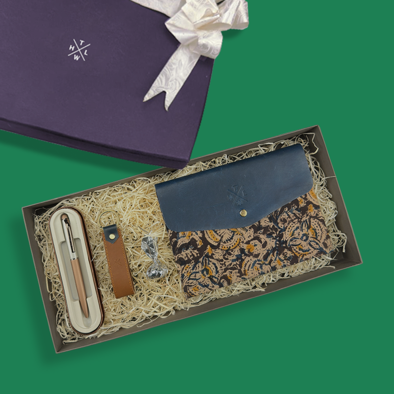 Gift set with a blue pouch, pen, and other items in a box on a green background