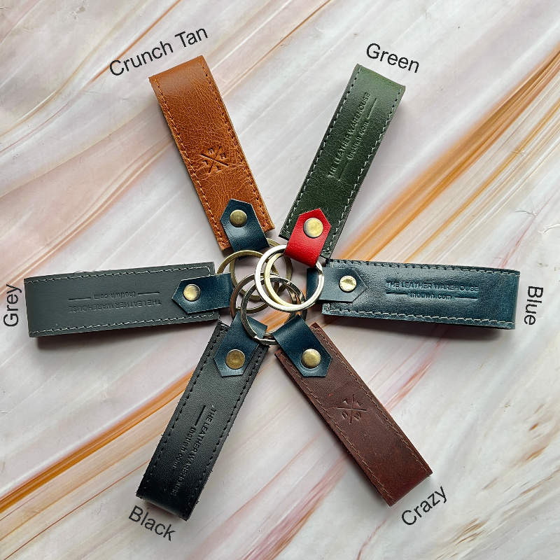 Keychain with leather straps in various colors on a light wooden surface