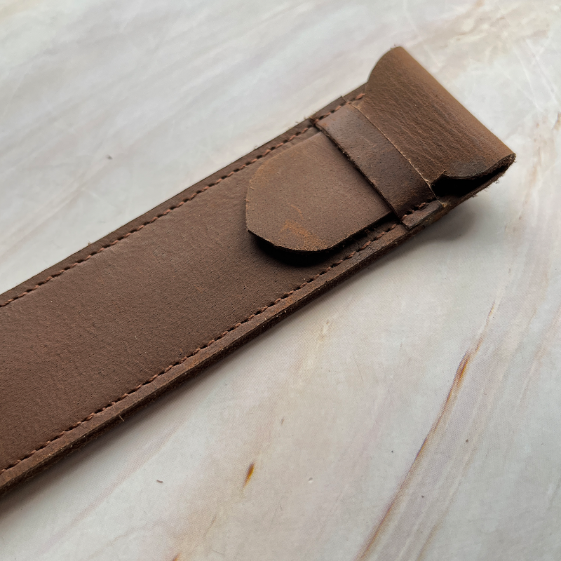 Brown leather strap on a light wooden surface