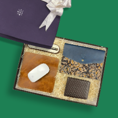 Gift set with leather items including a wallet, mouse pad, and mouse on a green background.