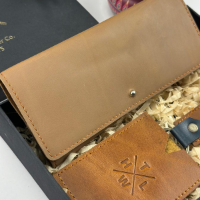 Brown leather wallet with 'TLWH' logo on a textured surface