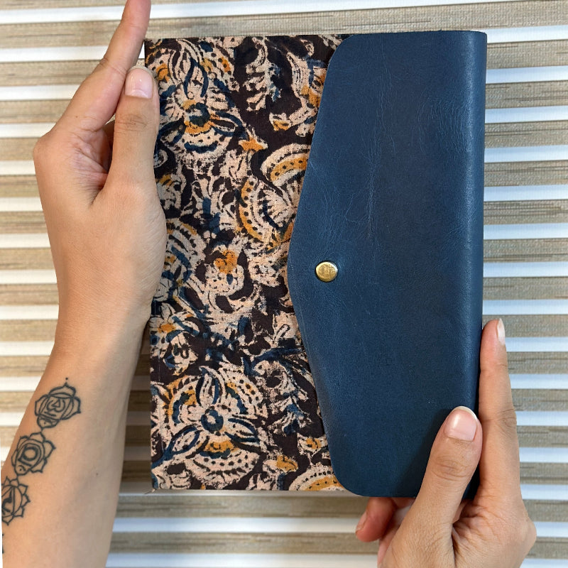 Person holding a blue wallet with a patterned fabric background