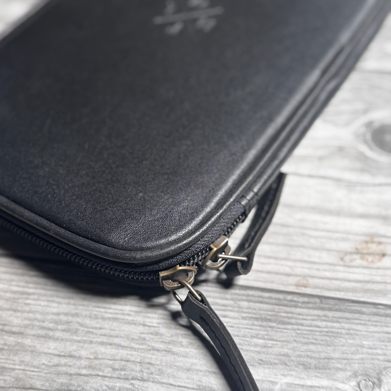 Black leather pouch with zipper on a wooden surface