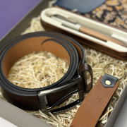 Brown leather belt with black buckle on a textured surface