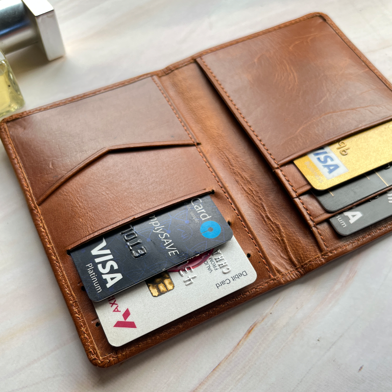 Brown leather wallet with various cards inside on a light wooden surface