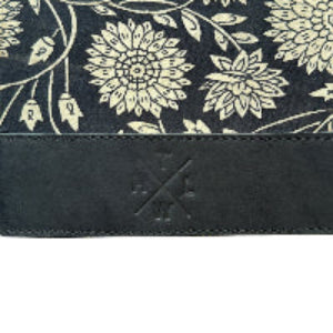 Floral patterned fabric with a leather strap and branding on a white background