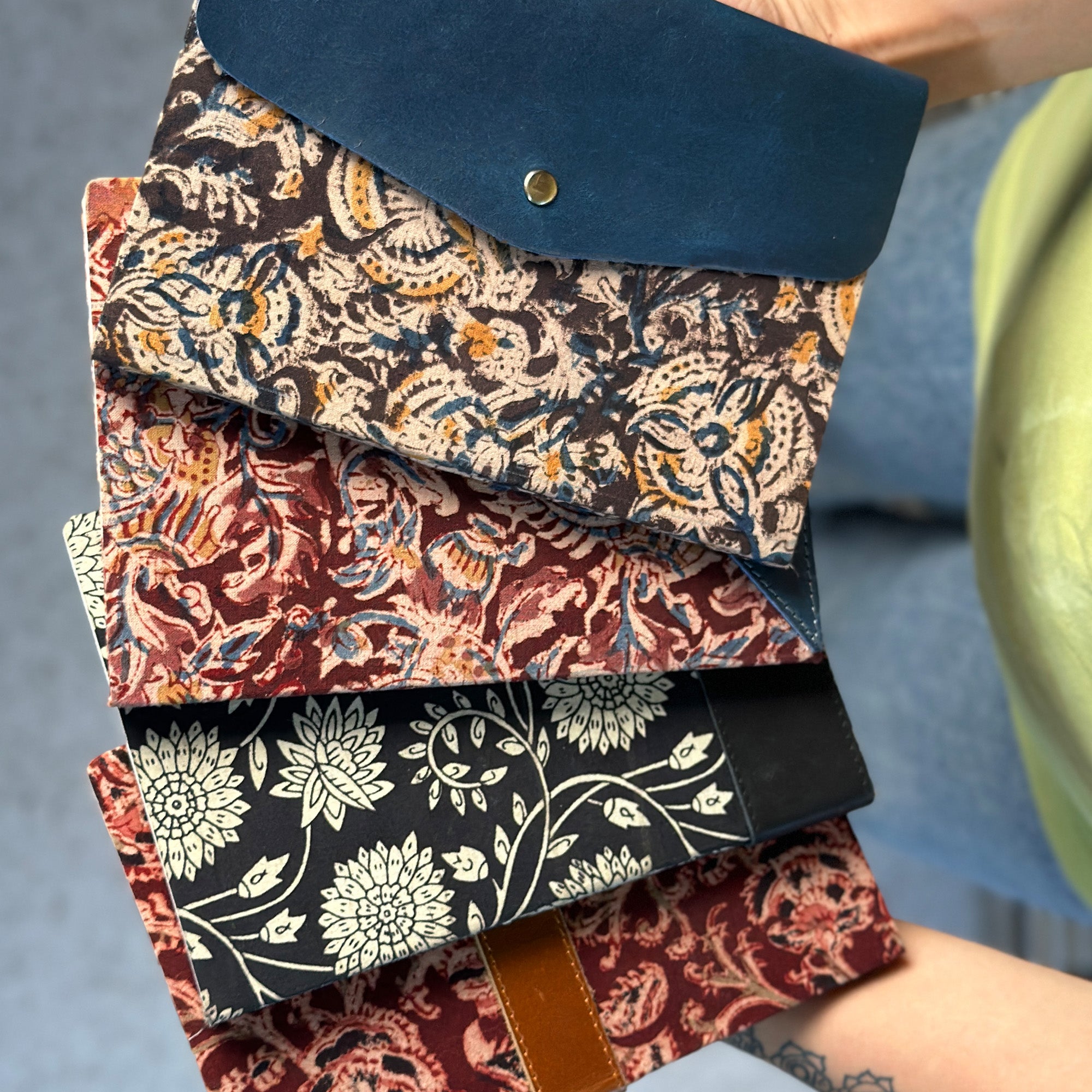 Stack of patterned books held by a person with a blurred background