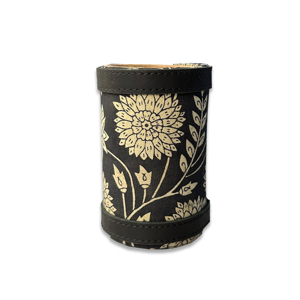Black cylindrical container with gold floral pattern on a white background