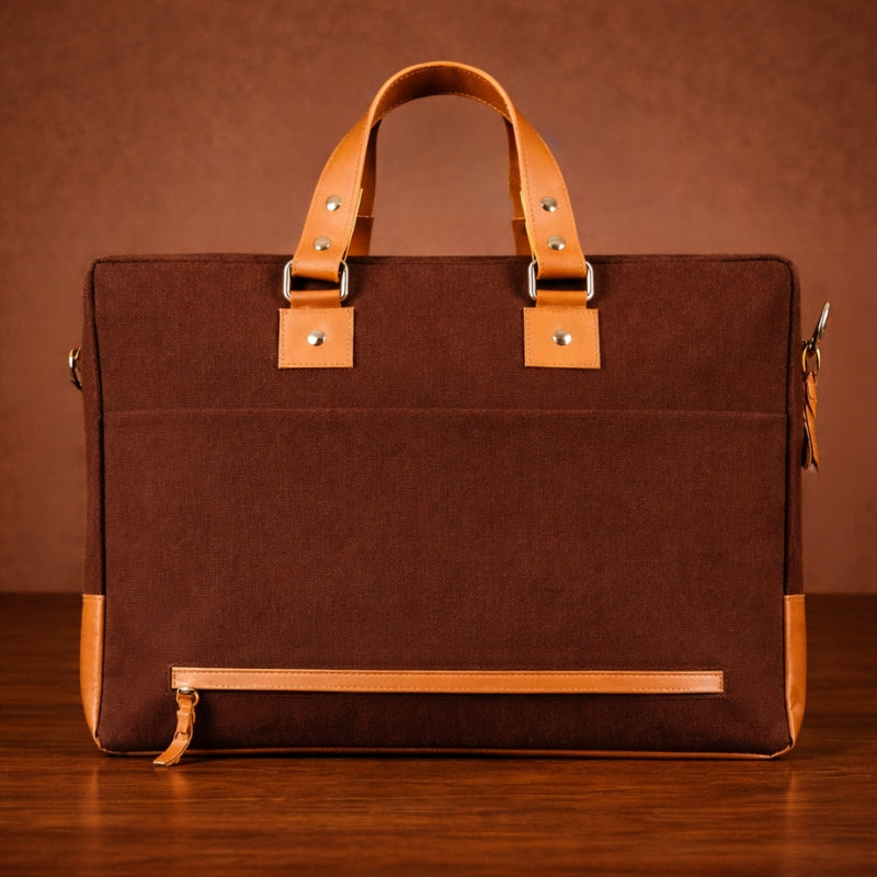 Brown canvas & leather briefcase with tan handles and trim on a wooden surface.