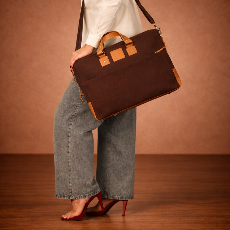 Person holding a brown canvas & leather briefcase against a brown background
