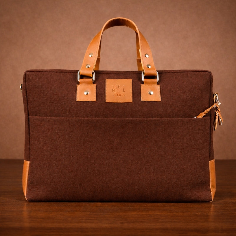 Brown canvas briefcase with tan leather handle and trim on a brown background