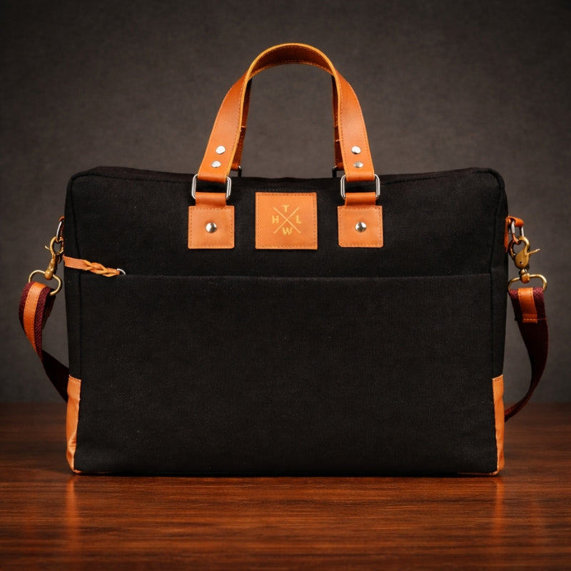 Black bag canvas with brown leather straps on a wooden surface