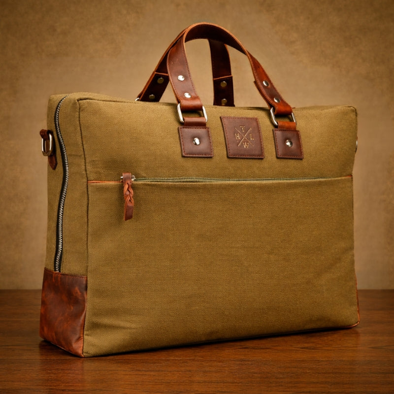 Brown leather and canvas bag with brown leather straps on a wooden surface.