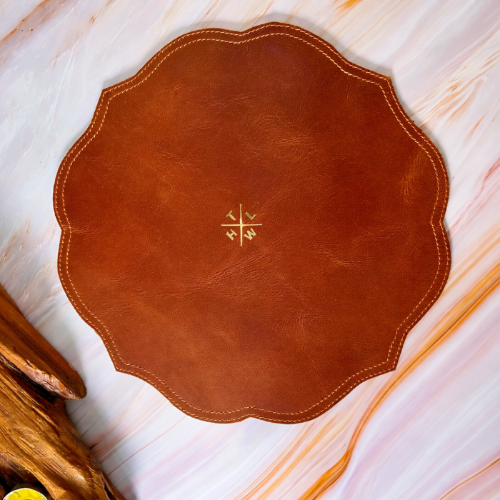 Brown leather placemat with a central design on a marble surface
