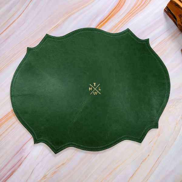 Green leather placemat with a logo on a light wooden surface