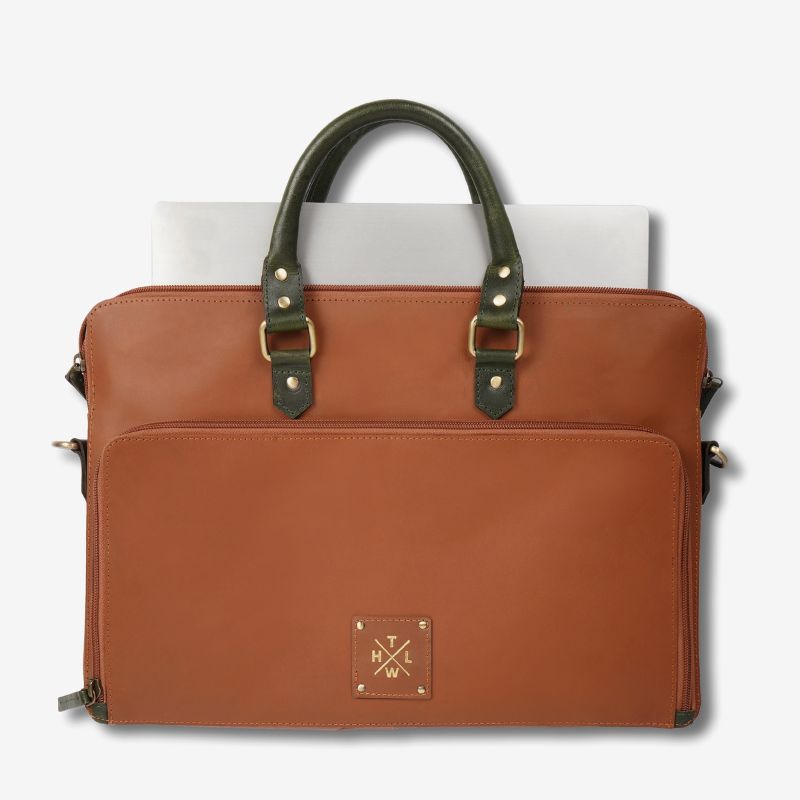 Front view of a brown leather laptop bag with navy handles and shoulder strap.