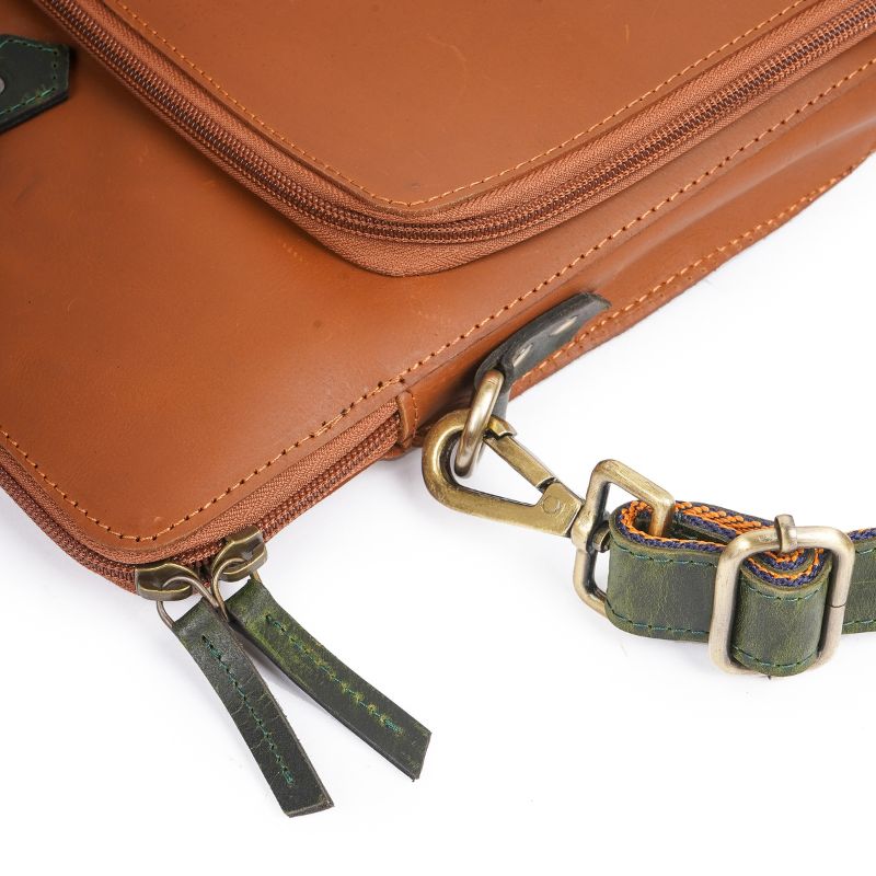 Close-up of the brown leather laptop bag’s shoulder strap and metal buckle.