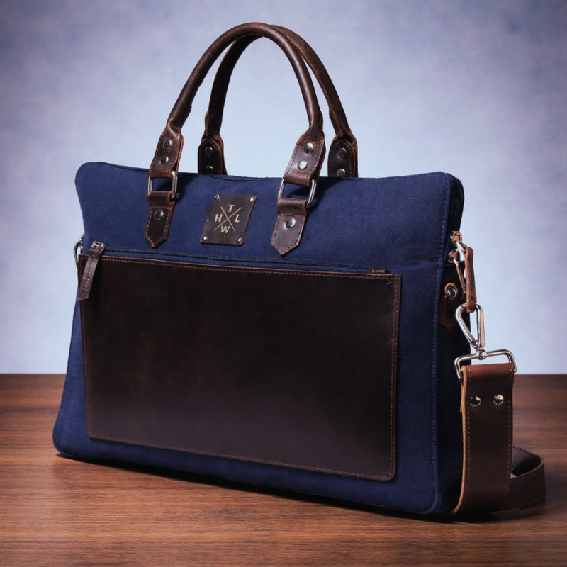 Blue canvas handbag with brown leather accents on a wooden surface