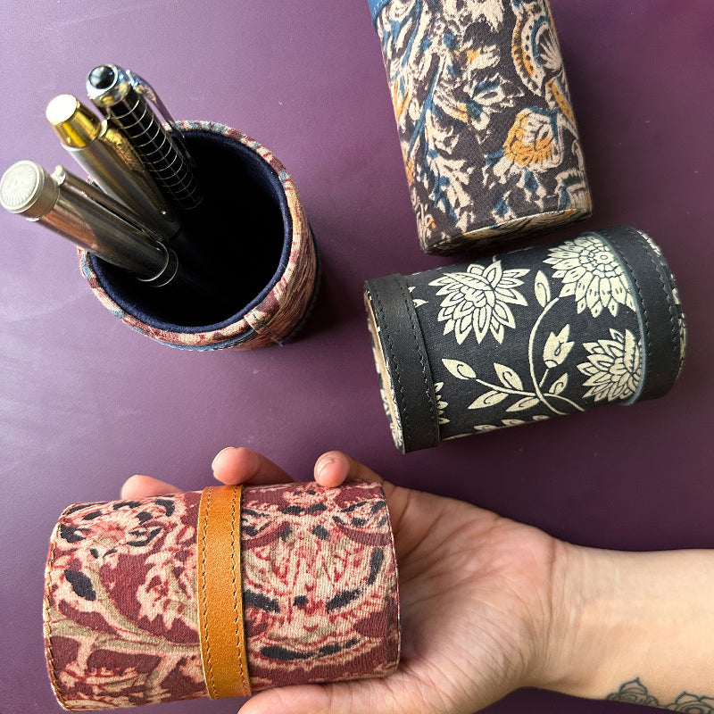 Decorative pen holder with floral patterns on a purple surface