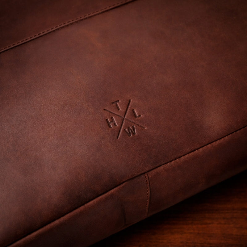 Close-up of a brown leather product with an embossed logo on a wooden surface
