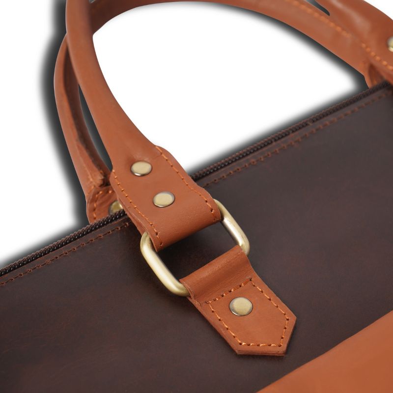 Close-up of a brown leather laptop bag with a strap and gold buckle on a white background