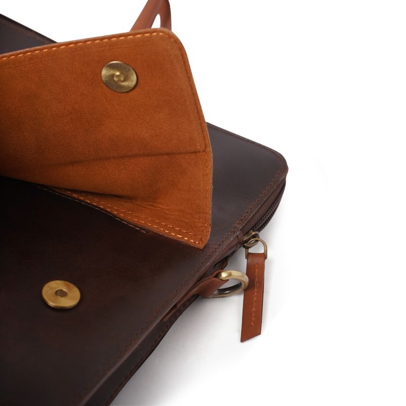 Brown leather laptop bag with gold accents on a white background