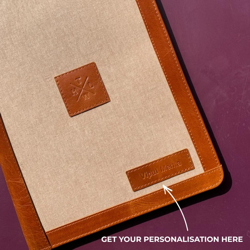Beige and brown leather-bound notebook with a visible brand logo on a purple background