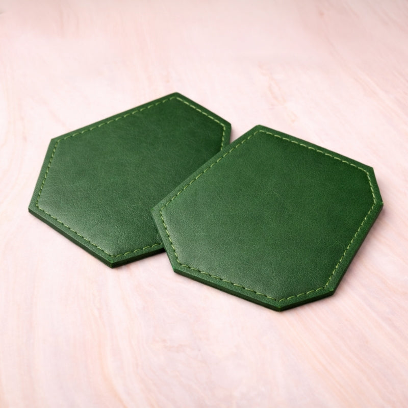 Two green hexagonal coasters on a light pink surface