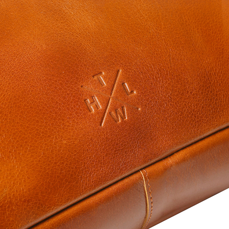 Close-up of a brown leather product with a logo embossed on it.
