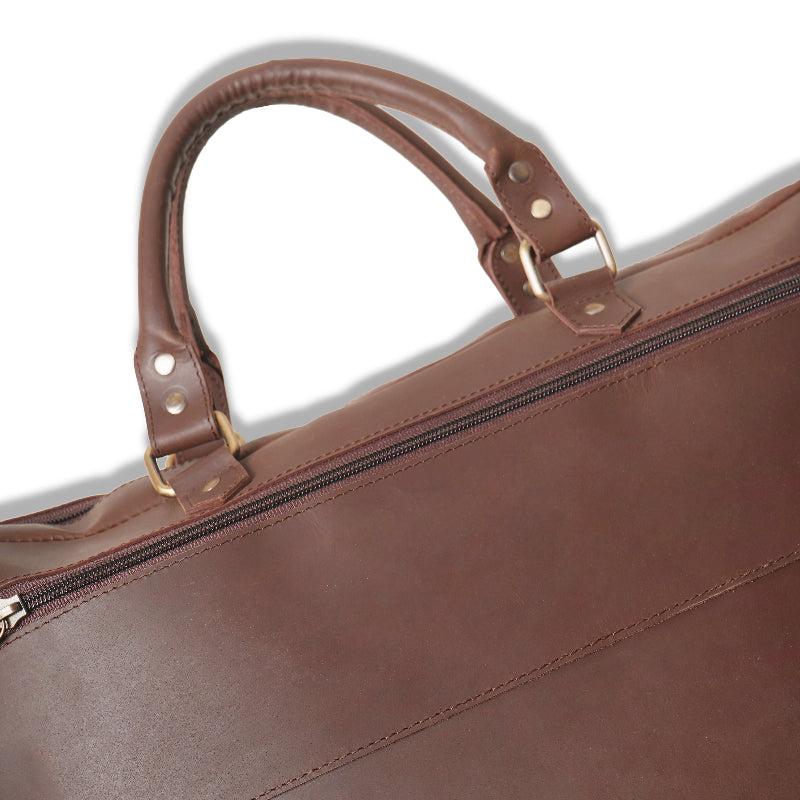 Brown leather bag with handle and zipper on a white background