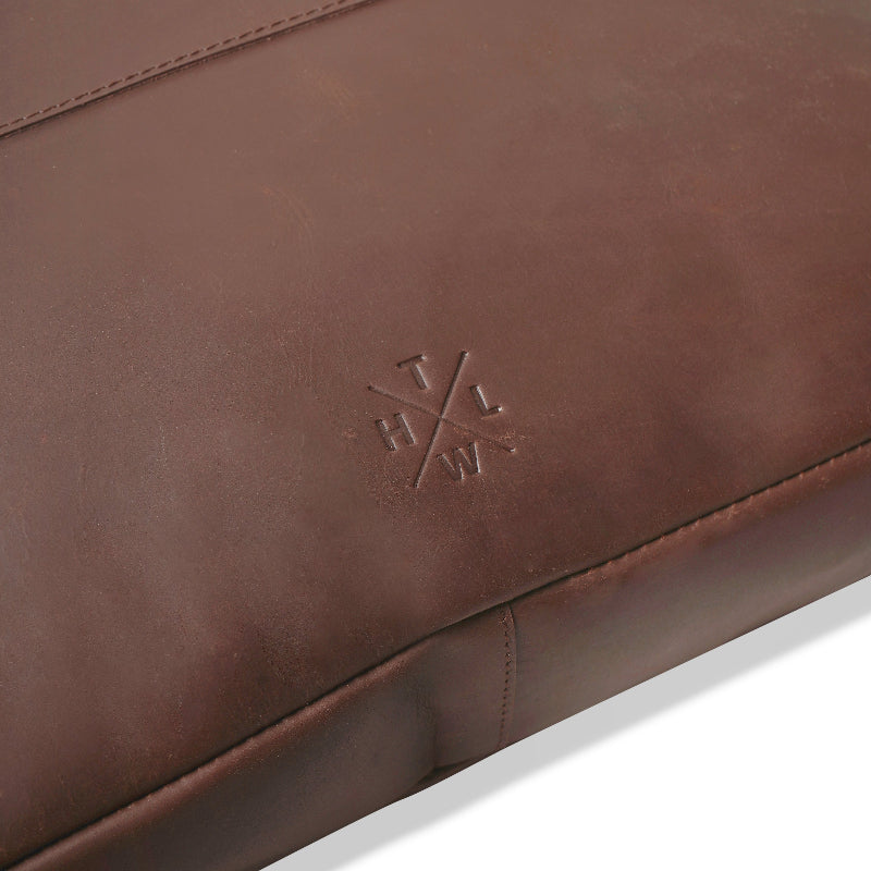 Close-up of a brown leather product with a logo on a white background