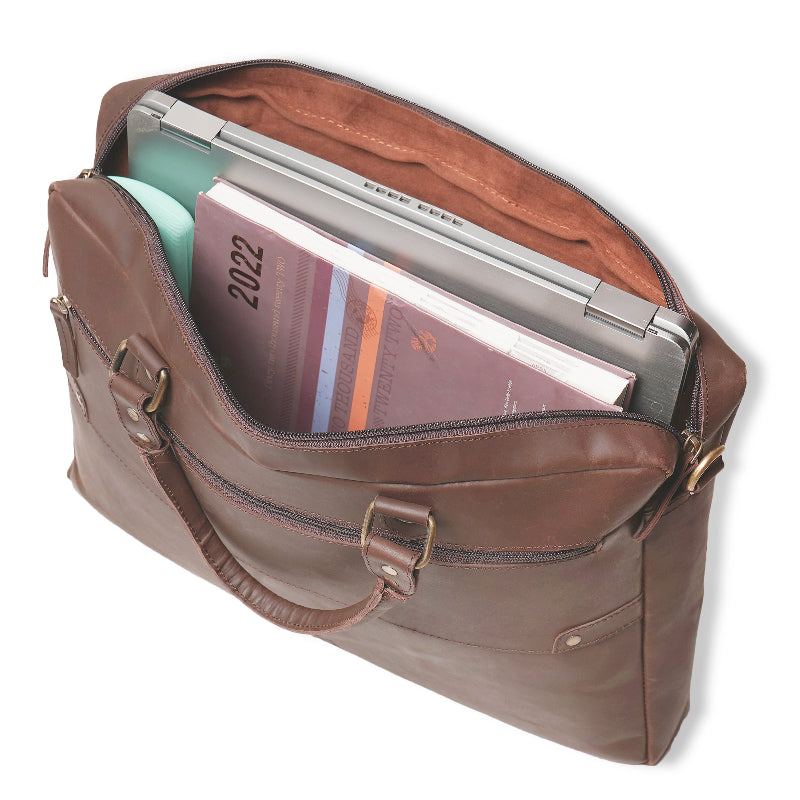 Brown leather briefcase with a laptop and books inside on a white background