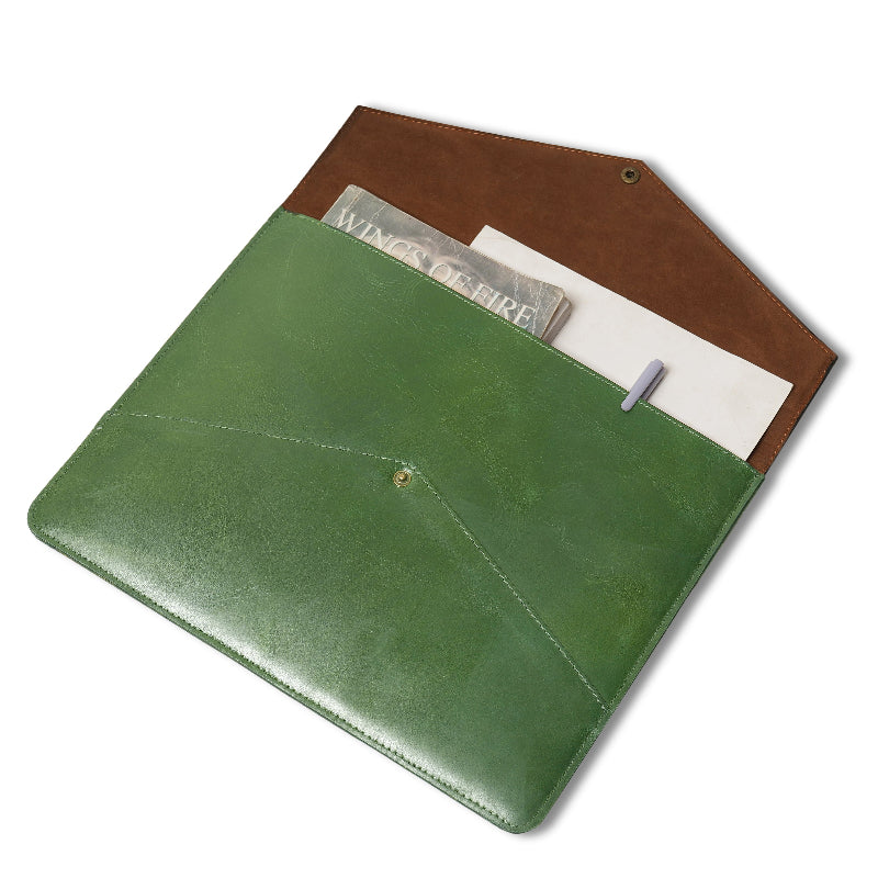 Two-tone leather sleeve with a green front pocket and brown back, containing a magazine and pen.