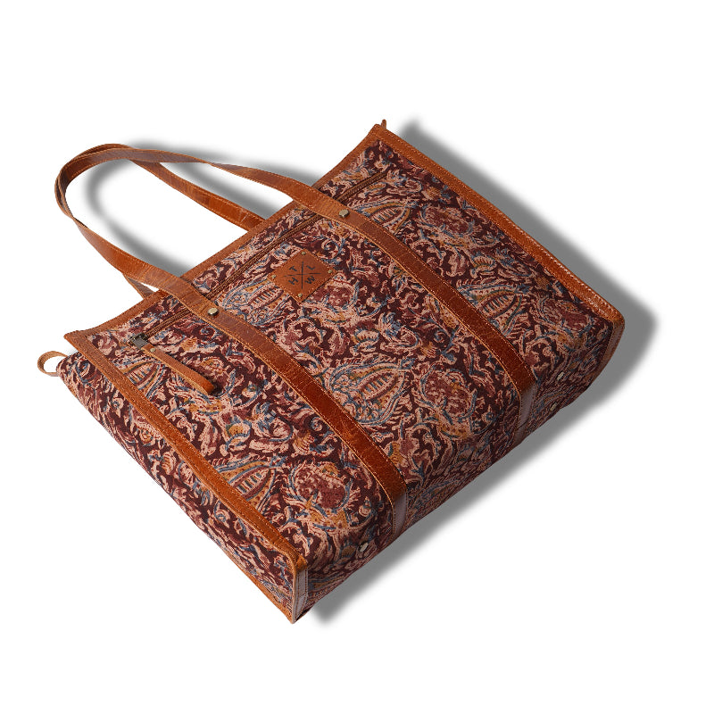 Brown leather tote bag with intricate patterns on a white background