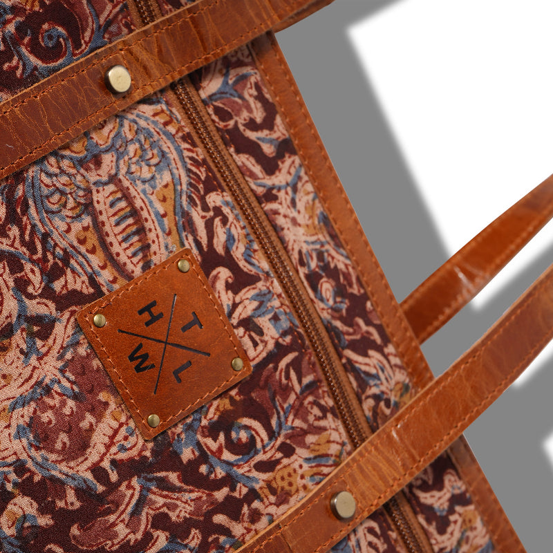 Close-up of a patterned bag with leather strap and visible brand logo.