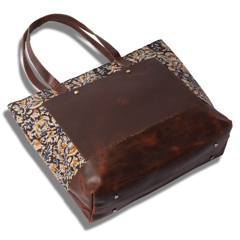 Brown leather tote bag with floral patterned side panels on a white background