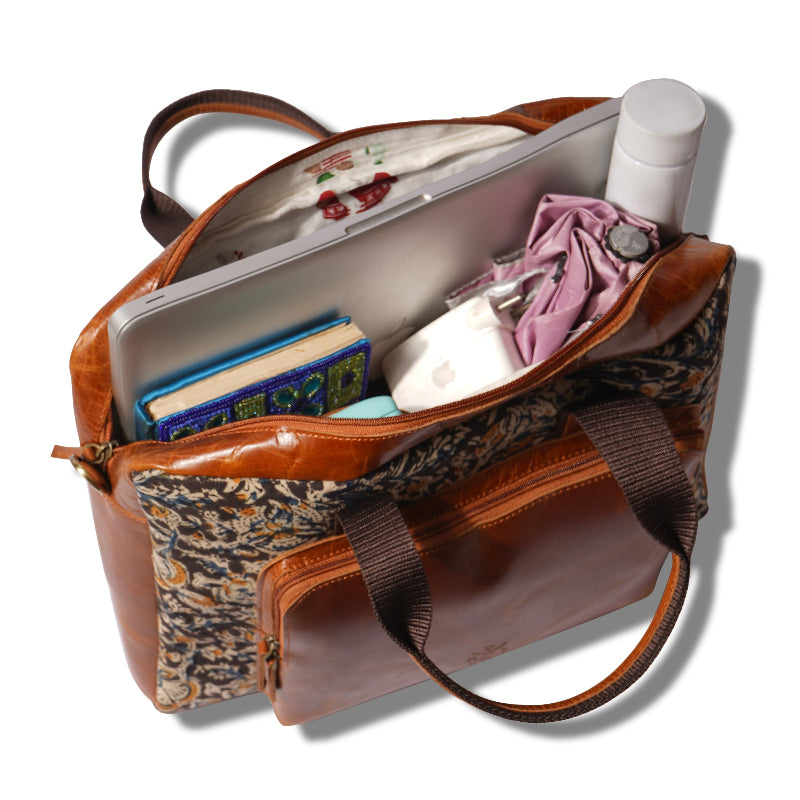 Brown leather handbag with floral lining containing books, a bottle, and an umbrella on a white background