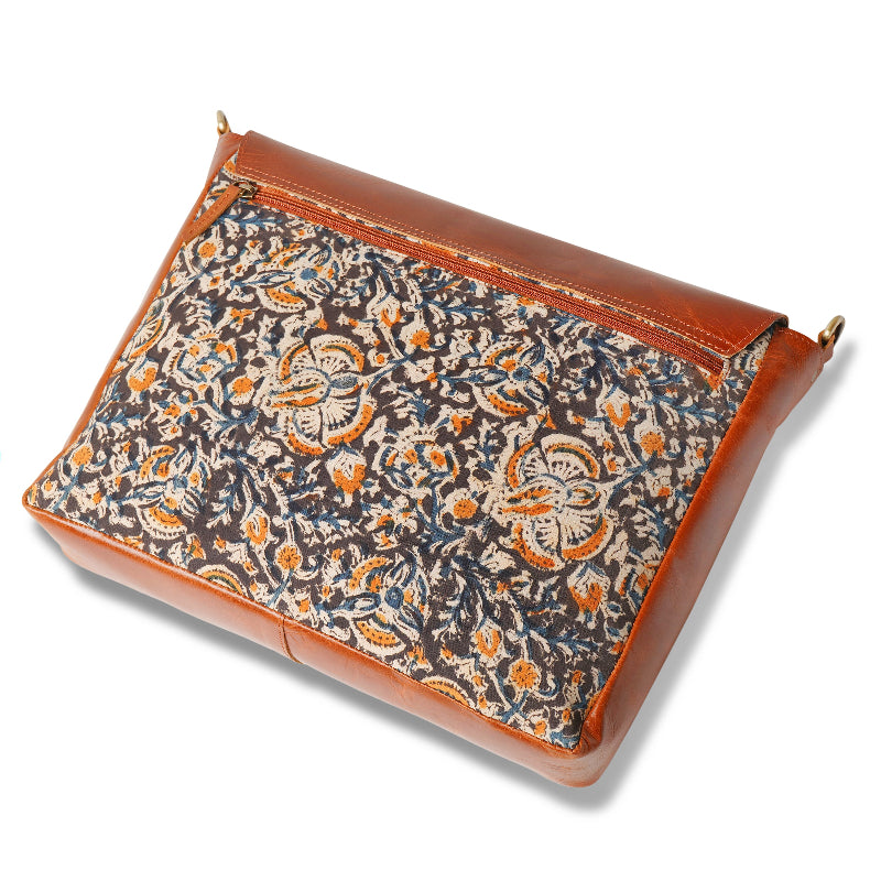 Floral patterned clutch bag with brown leather trim on a white background
